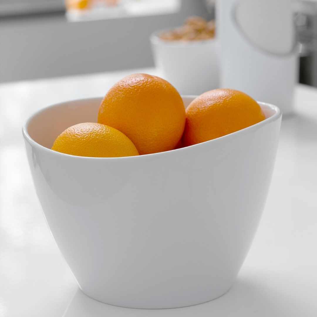 Appelsiner i en hvid skål på et lyst køkkenbord
