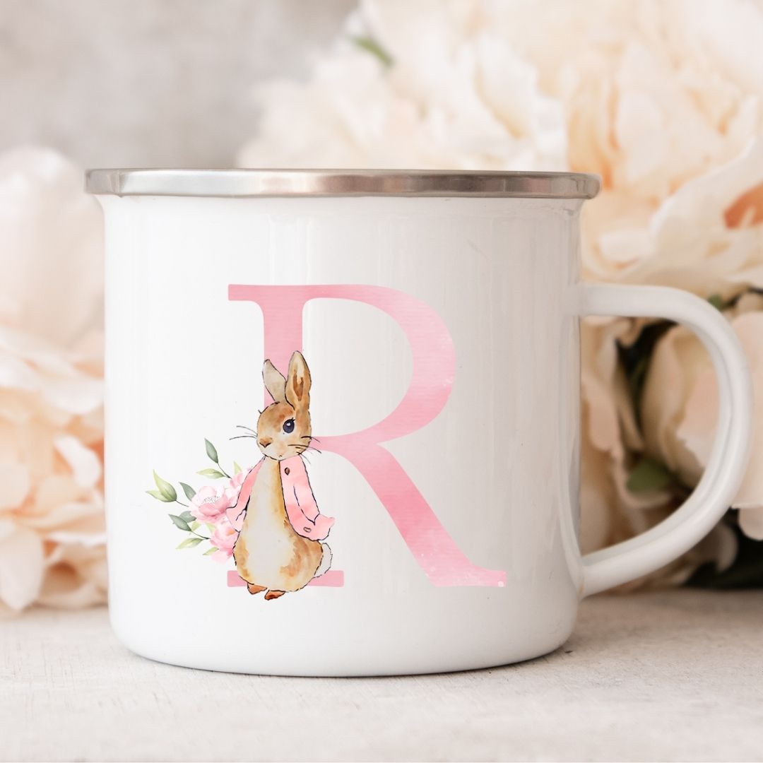 Hvid metalkop med bogstavet R i rosa og illustration af en kanin