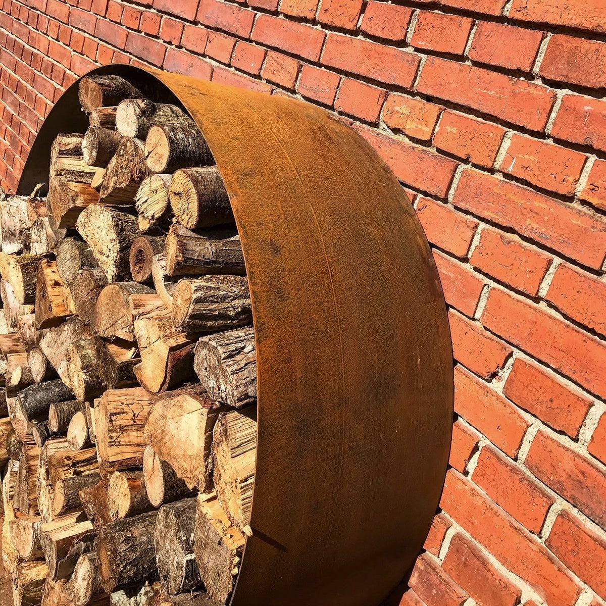 Stort sortmalet væghængt brændeskjul i cortenstål fra Jernbede, diameter 127 cm, med skillerum